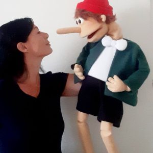 Foto von Sonja Otti mit einer Klappmaulpuppe in Form von Pinocchio, sie schauen sich tief in die Augen